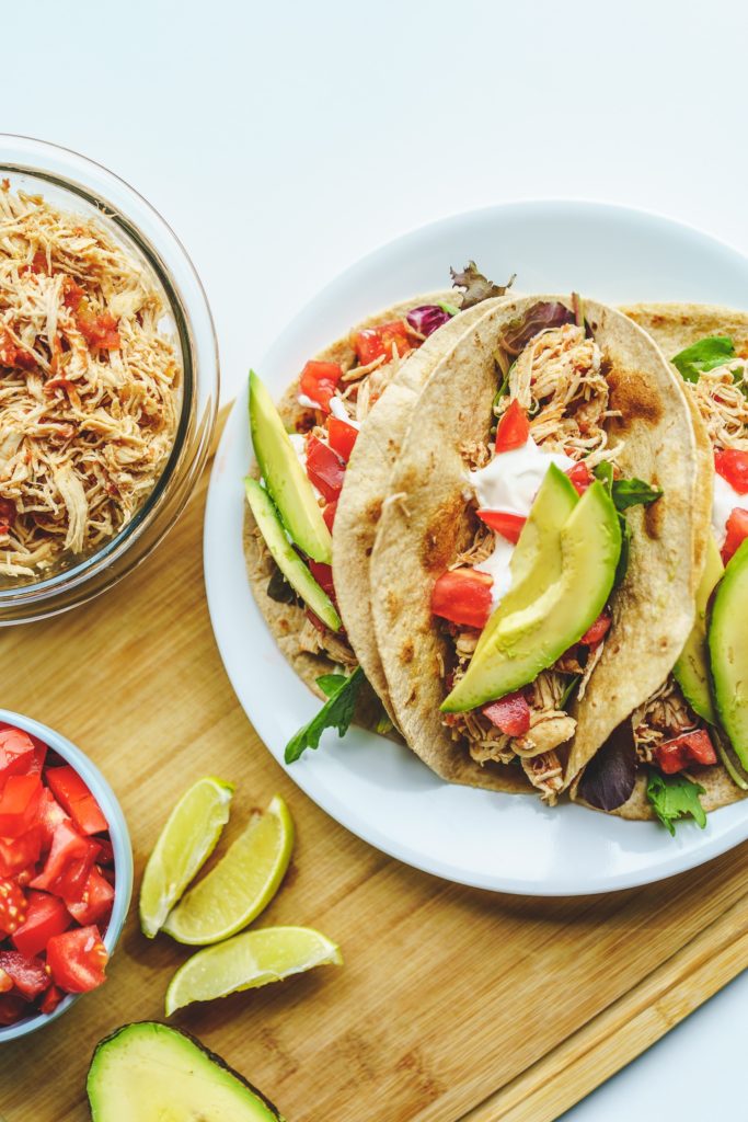 tacos on plate with bowl of shredded chicken