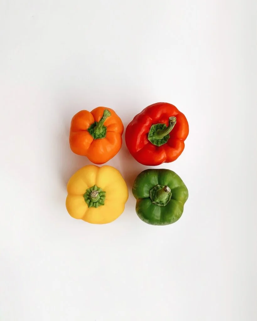 four multicolor bell peppers against white background