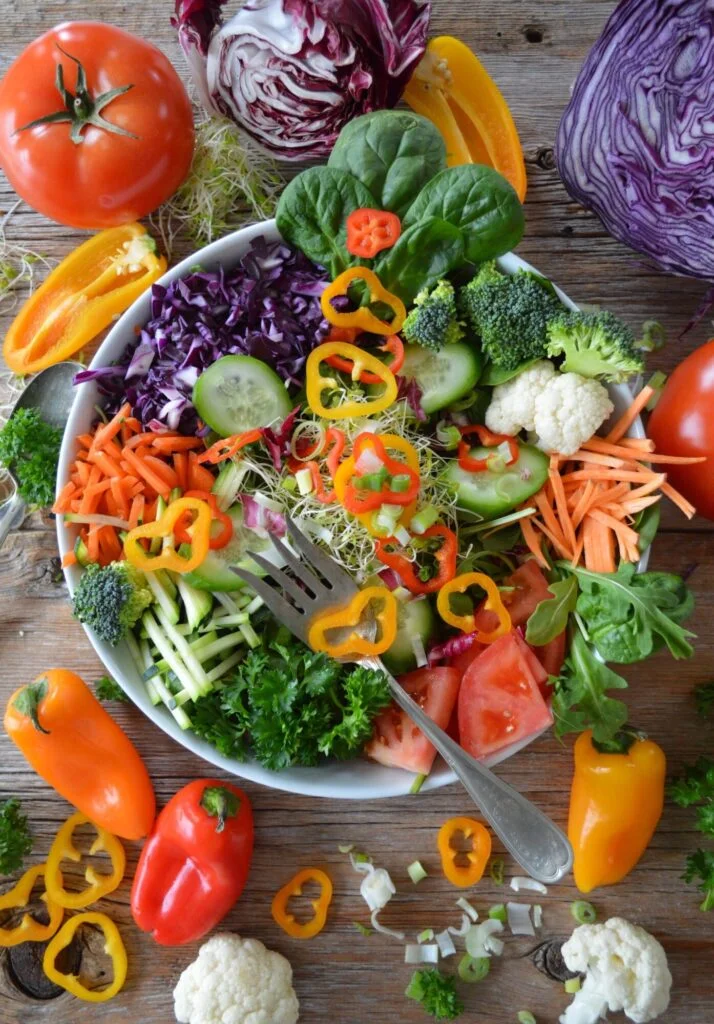 colorful salad bowl surrounded by chopped vegetables