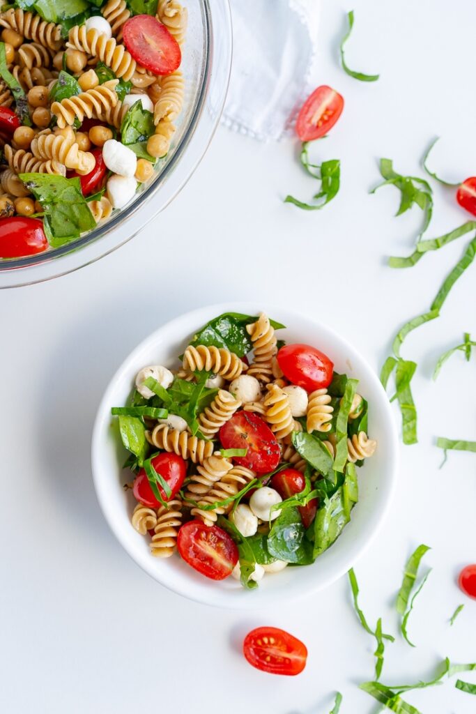 bowls of pasta salad with tomatoes and spinach