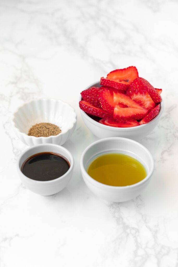 prep bowls with pepper, olive oil, balsamic vinegar, and strawberries