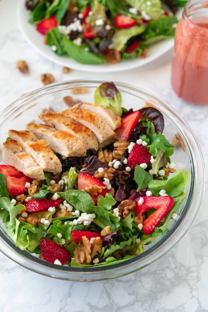 plate and bowl containing strawberry walnut salad with chicken