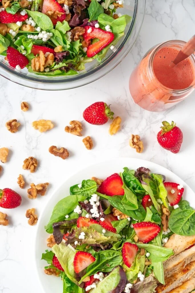 plate and bowl containing strawberry walnut salad