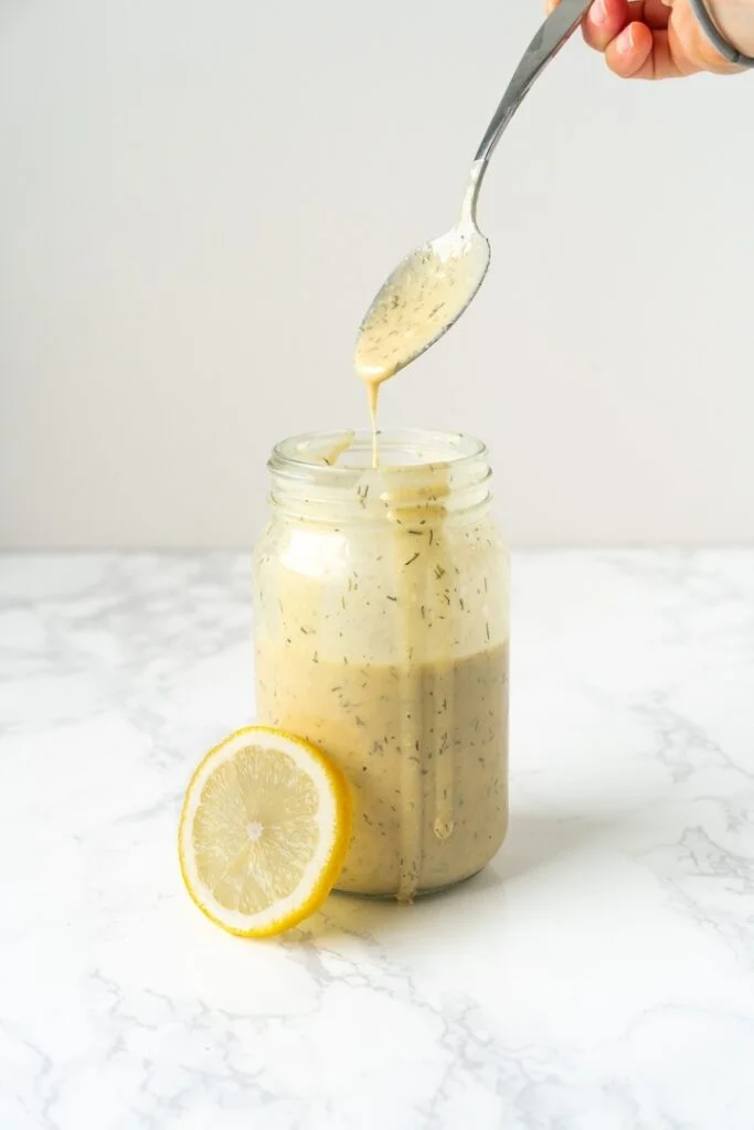 jar with creamy dressing, lemon slice, and a dripping spoon