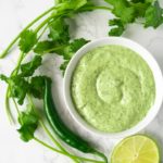 bowl of cilantro lime sauce with fresh cilantro, green pepper, and lime slice