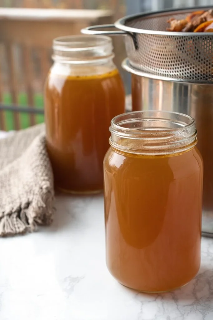 jars with instant pot bone broth and strainer in background