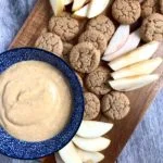 yogurt dip in bowl on tray with cookies and apple slices