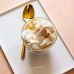 white tray with gold spoon and latte with whipped topping