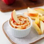 apple slice dipping into cup with caramel dip