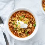 bowl of chicken chili topped with cornbread and sour cream