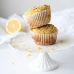two lemon poppyseed muffins stacked on white cake plate