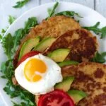 three slices of French toast topped with avocado tomatoes and fried egg