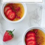 two ramekins with creme brûlée and strawberries