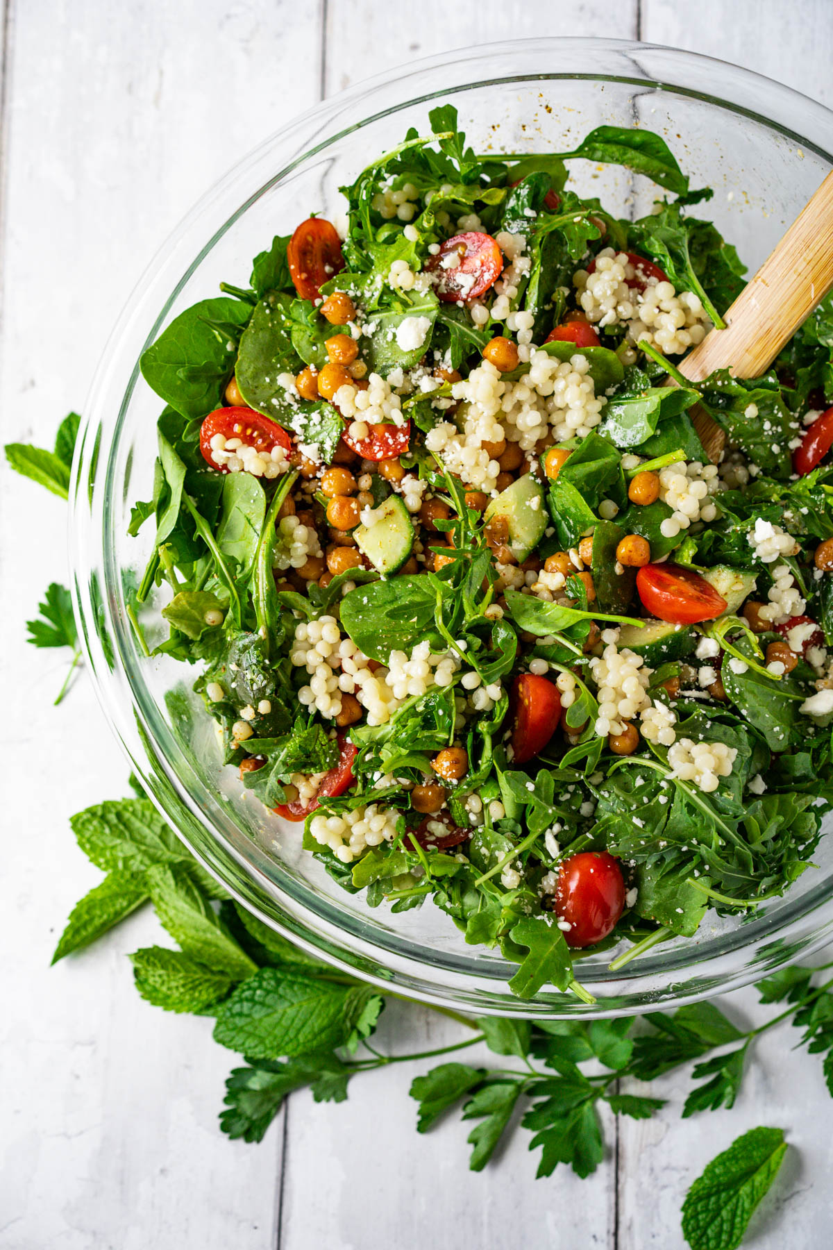 large bowl with mixing spoon and mixed couscous salad inside
