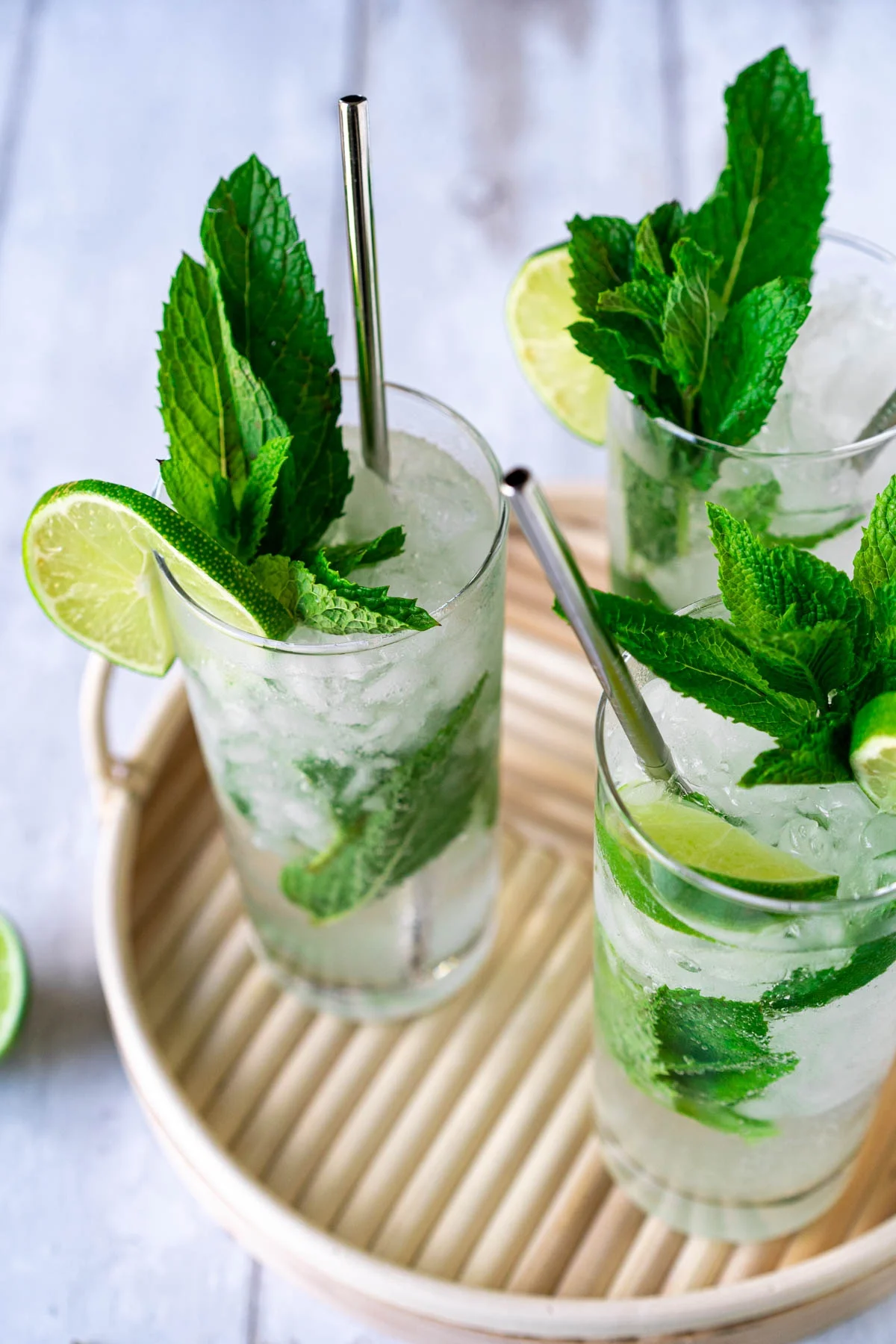 three glasses of non-alcoholic mojitos on a bamboo tray