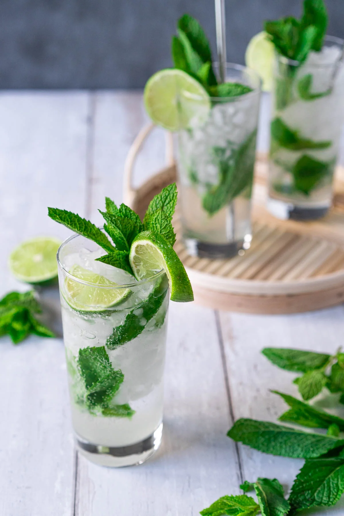 highball glass with mojito and tray of mojitos in background