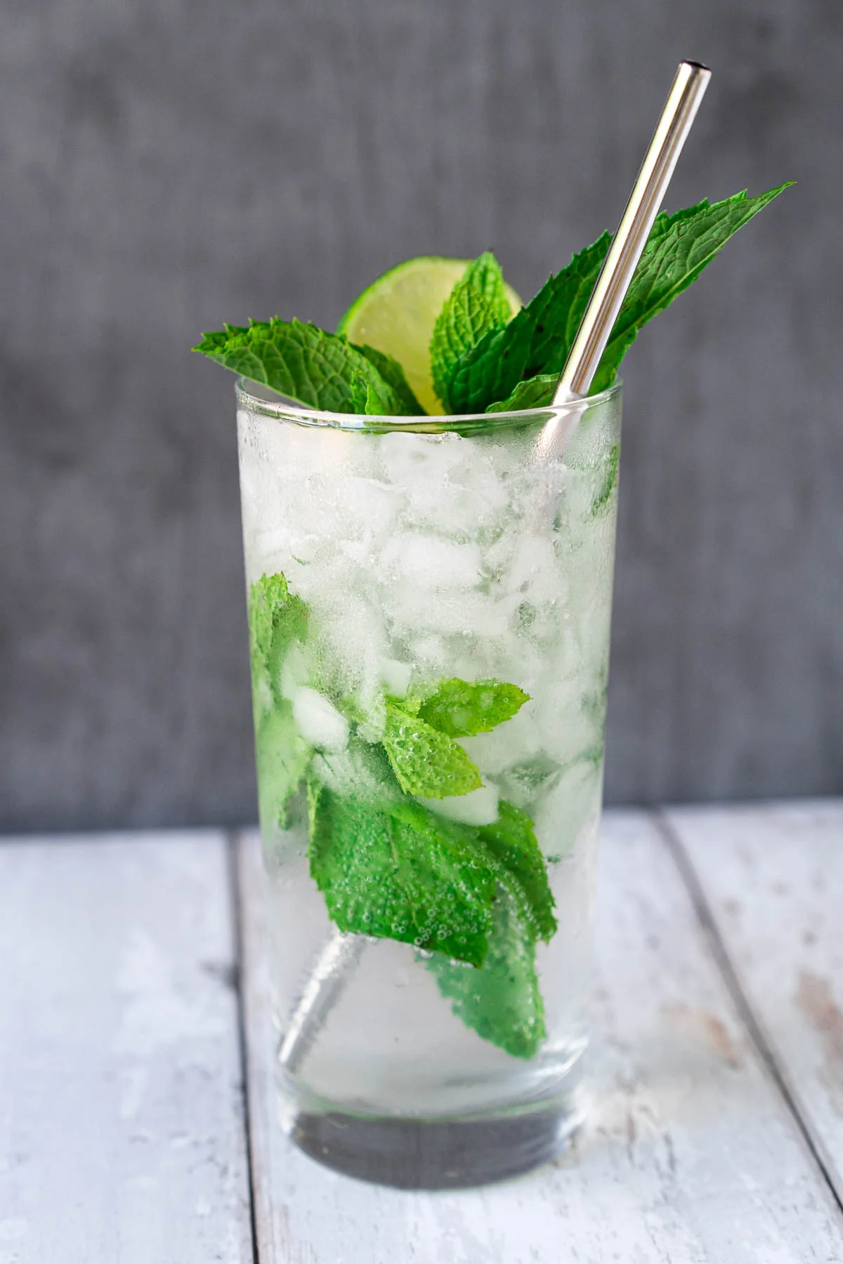 glass with crushed ice and mint, topped with lime and mint sprig and a silver straw