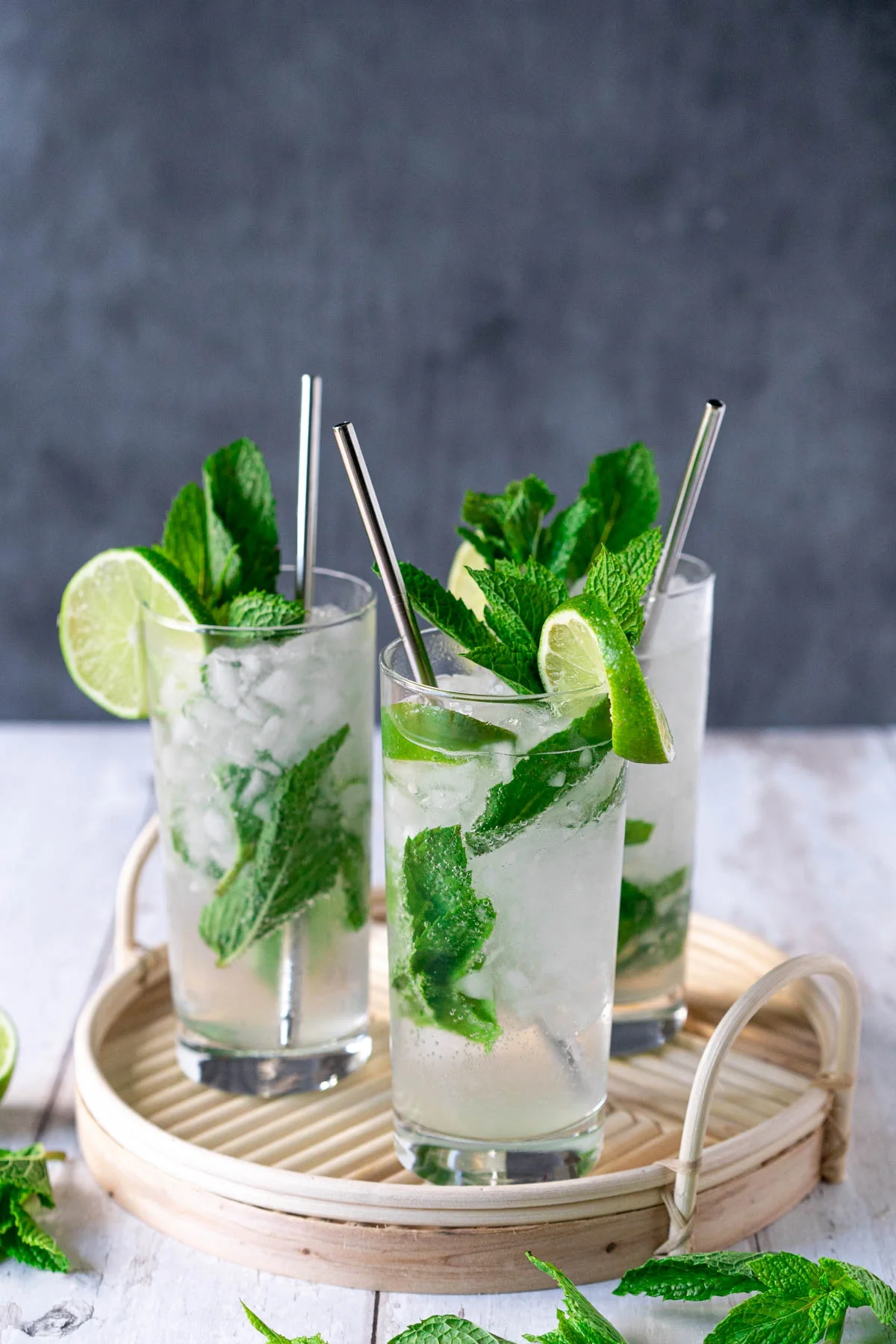 three glasses of non-alcoholic mojitos on a bamboo tray
