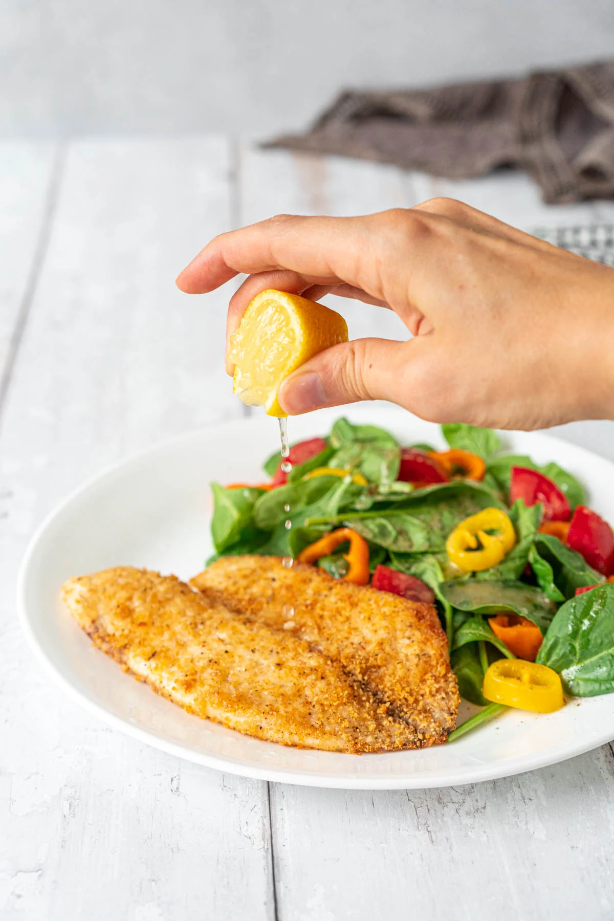 squeezing lemon on breaded fish