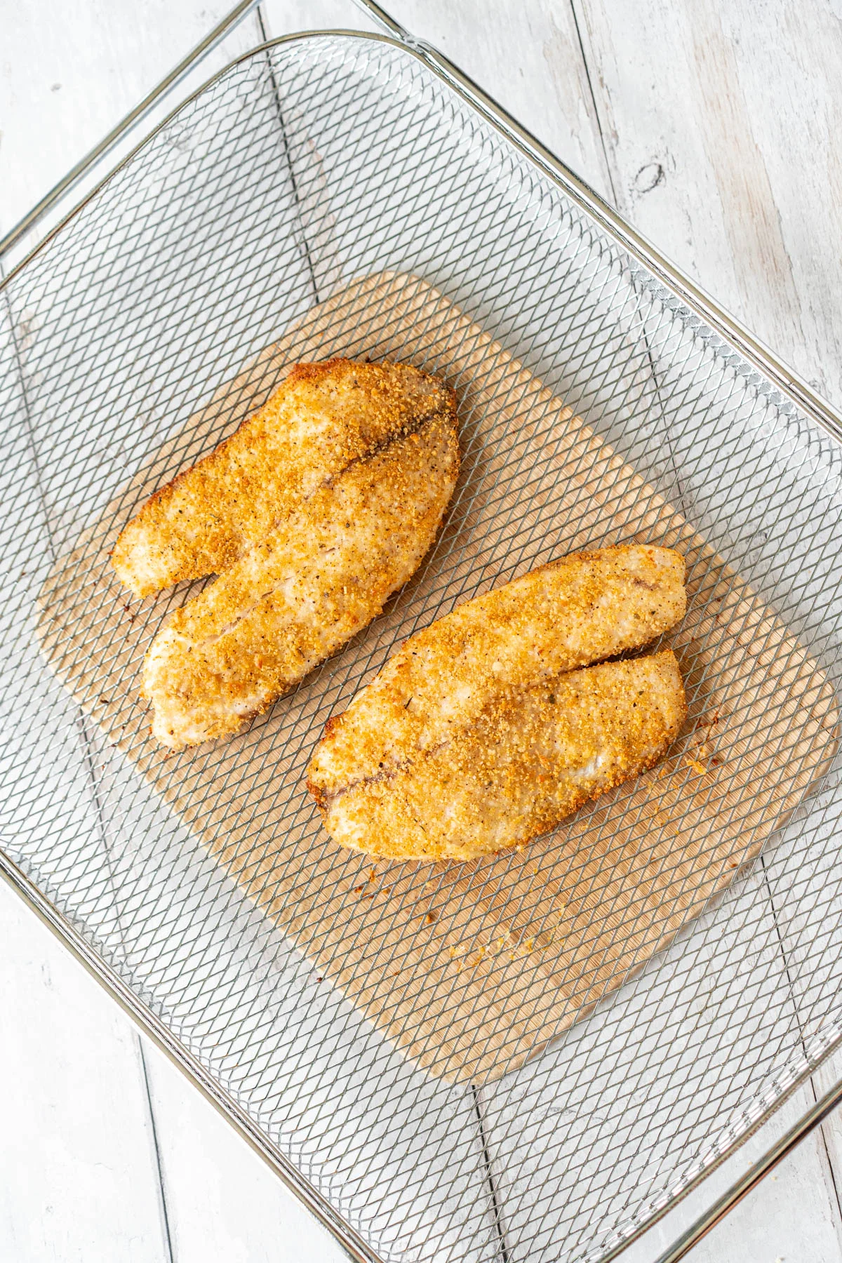 two breaded fish filets in an air fryer basket