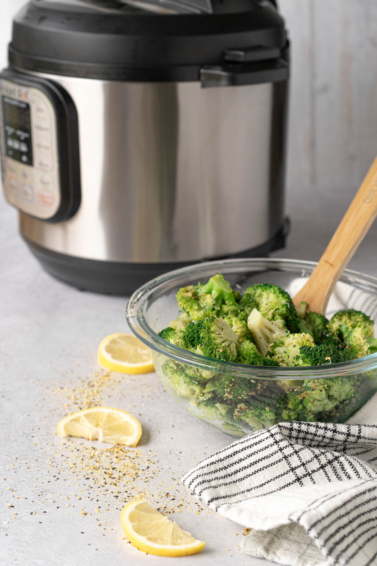 bowl of steamed broccoli with a pressure cooker in the background