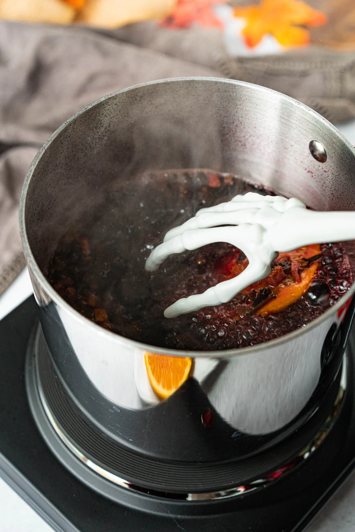 skeleton hand stirring a pot of mulled wine
