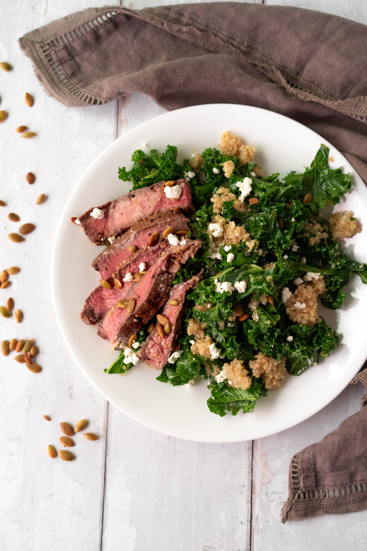 white plate with a kale salad and sliced steak