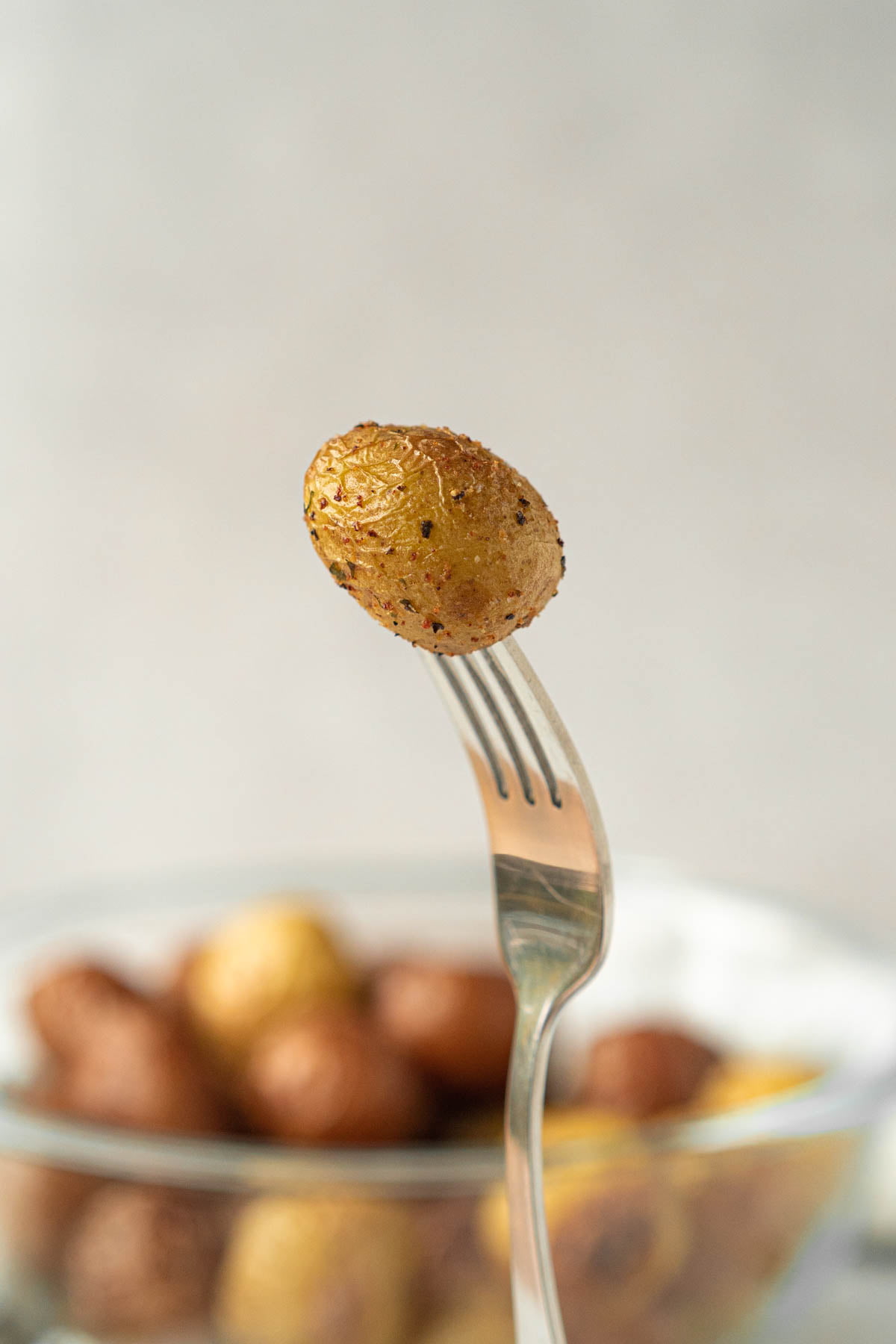 fork holding up a small seasoned potato