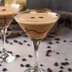 two martini glasses garnished with a chocolate drizzle and filled with dessert martini