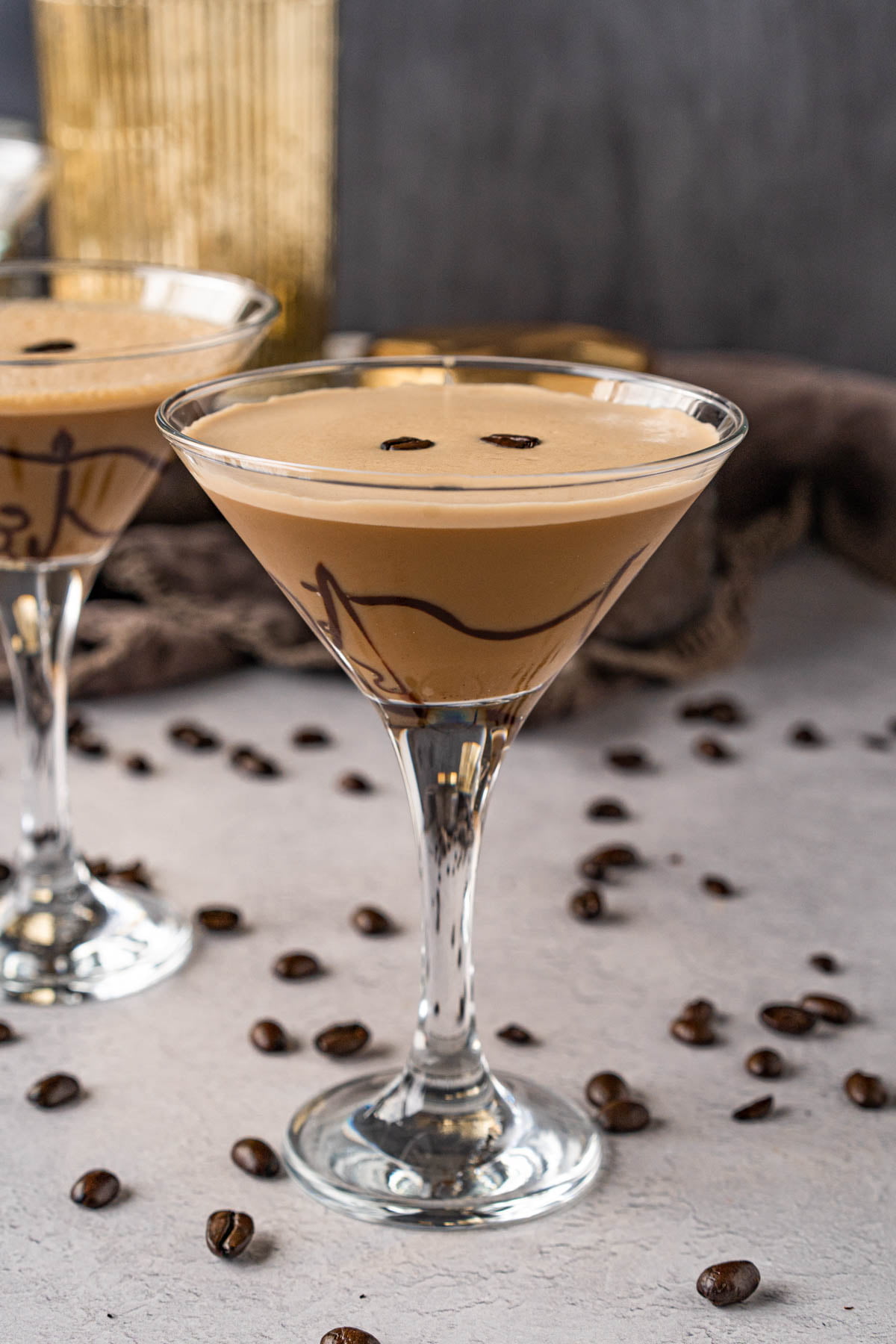 two martini glasses filled with coffee cocktail mixture and garnished with chocolate and coffee beans