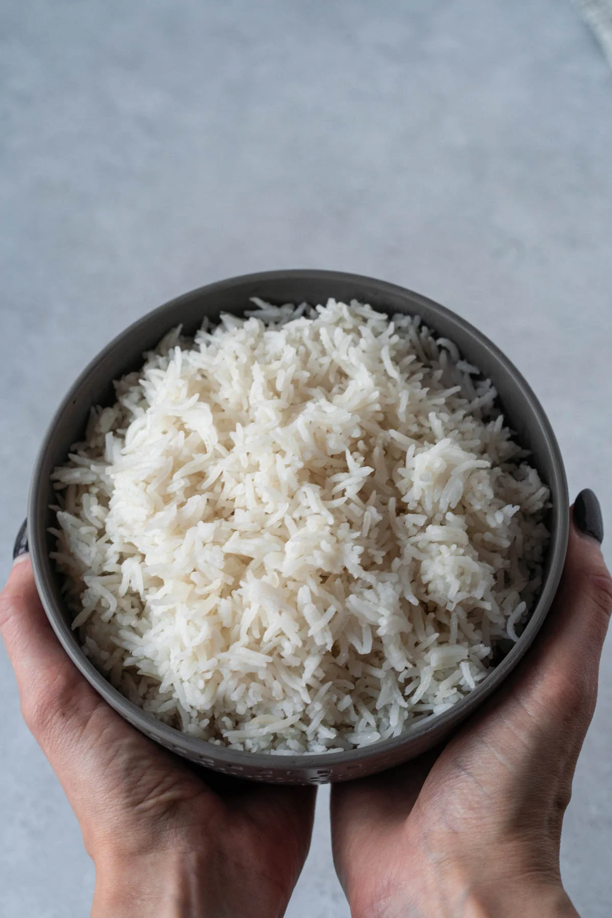 two hands holding a bowl of white rice