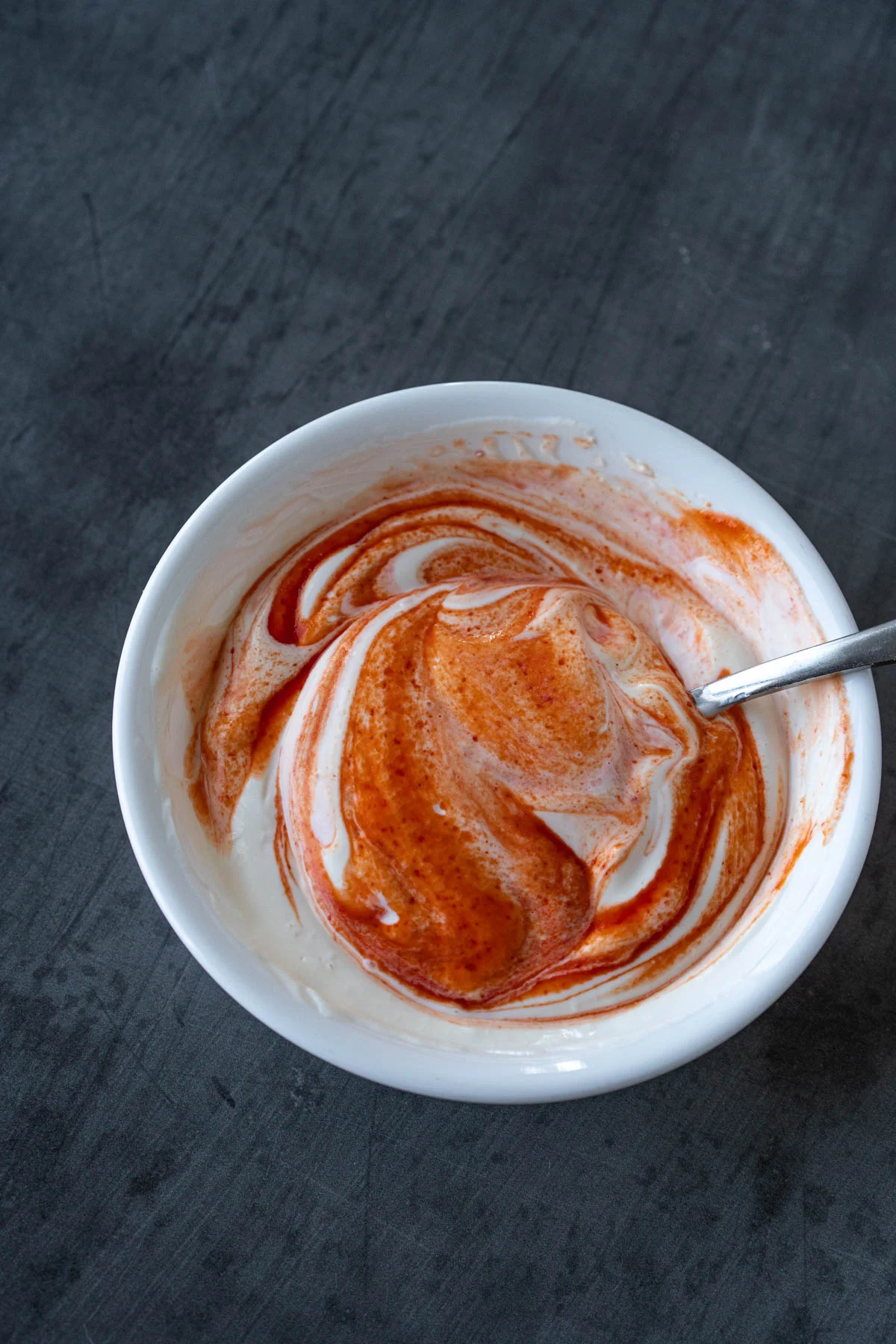 bowl of greek yogurt and mayo swirled with hot chili sauce