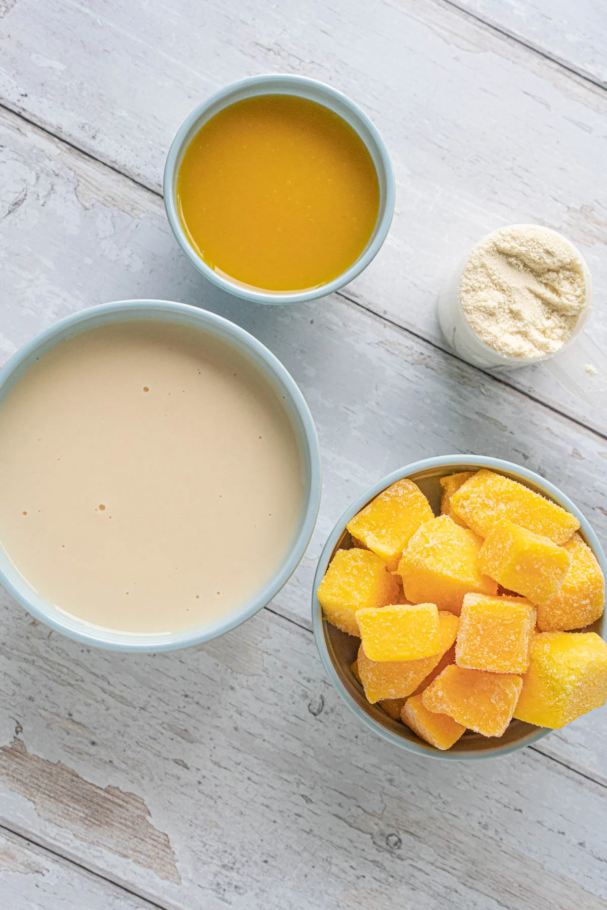 bowls with mango juice, soy milk, frozen mango, and protein powder