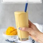 hand holding a glass of yellow smoothie