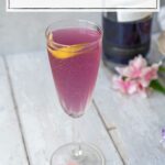 champagne flute filled with a light purple bubbly cocktail and garnished with a lemon twist