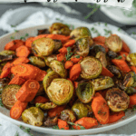 closeup side view of roasted sliced carrots and Brussels sprouts garnished with fresh thyme on a white plate against a white napkin and gray tabletop