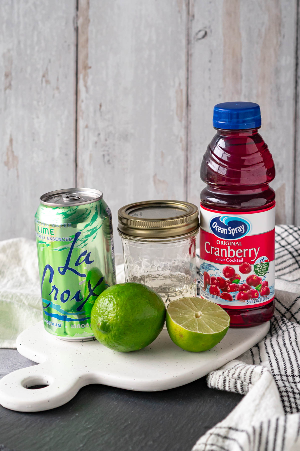 ingredients - can of lime sparkling water, jar of simple syrup, fresh lime, and bottle of cranberry juice cocktail